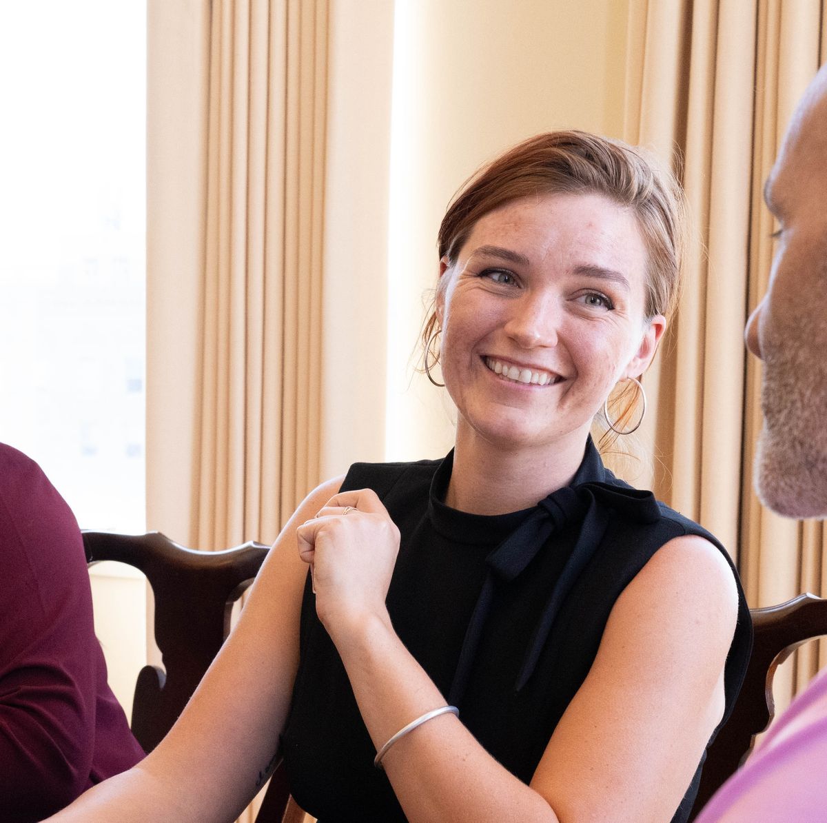 same red-headed woman smiling and talking with someone at a table